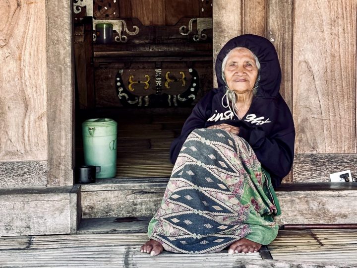 Woman sitting outside a traditional house in Bena Village