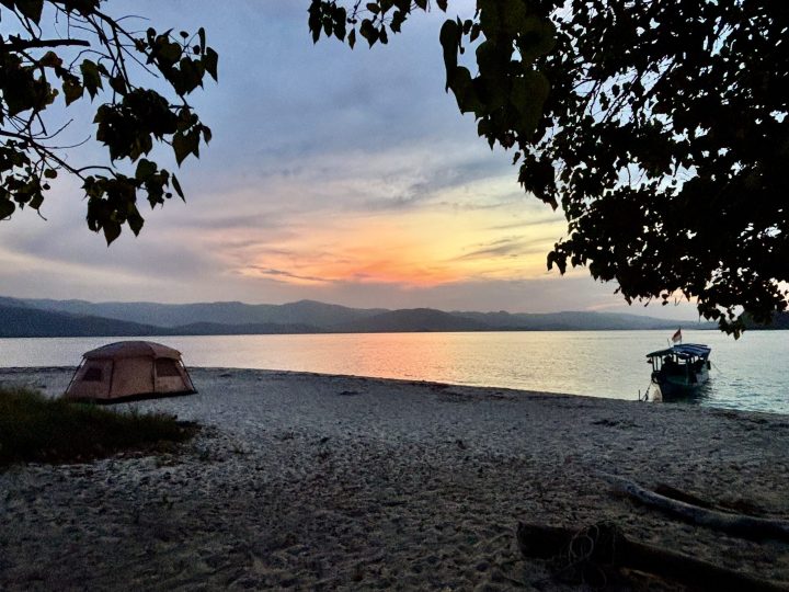 Tent boat and beach campsite at sunset on Nusa Bamba