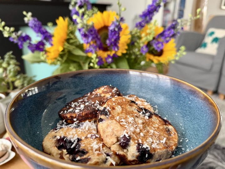 Healthy blueberry banana protein pancakes served on a plate with blueberries